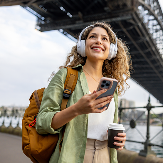 Woman using mobile phone walking under bridge