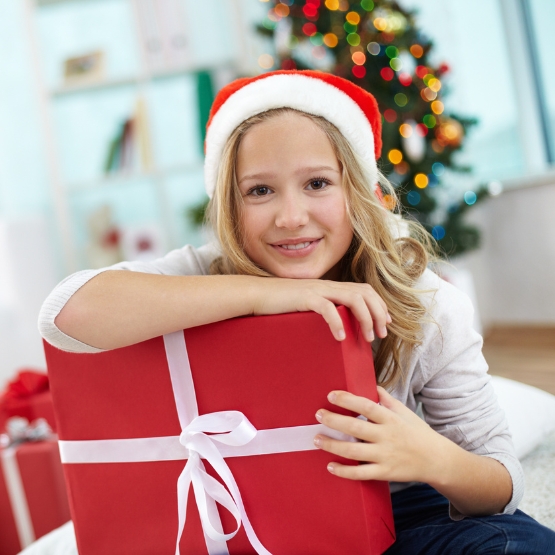 Girl holding present near Christmas tree