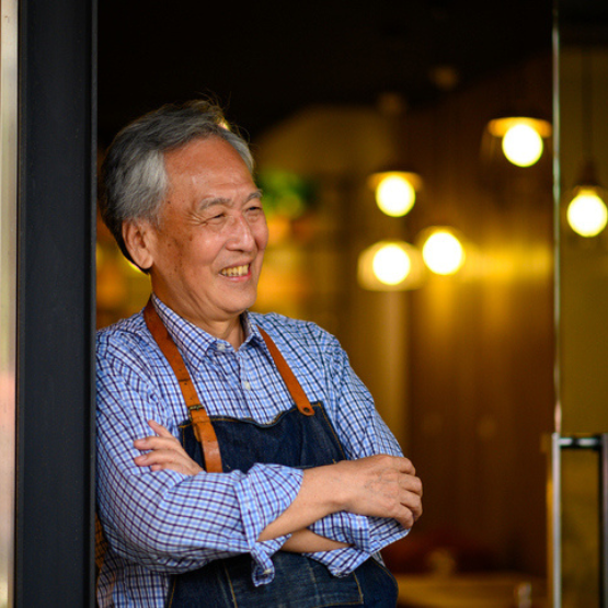 Person wearing apron leaning against restaurant doorway