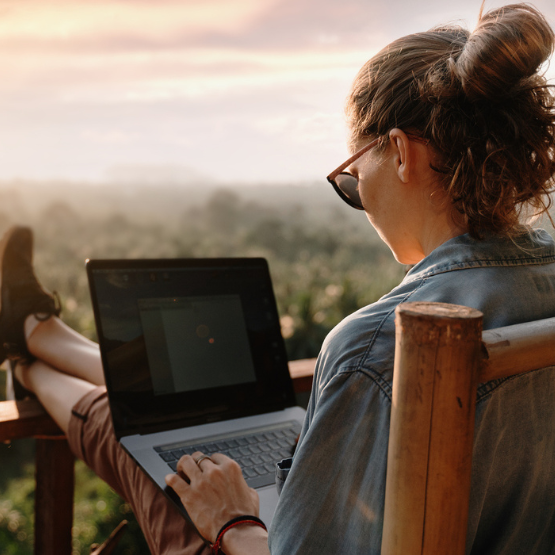 Person sitting outside on deck viewing laptop