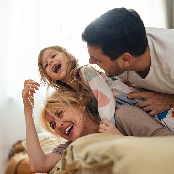 Mother and father playing with their daughter laughing